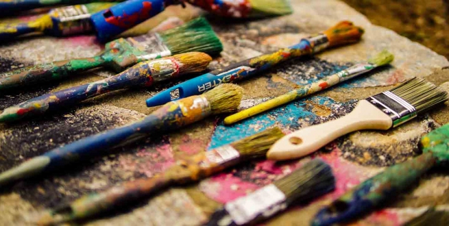 a dozen or so paint brushes on a table 